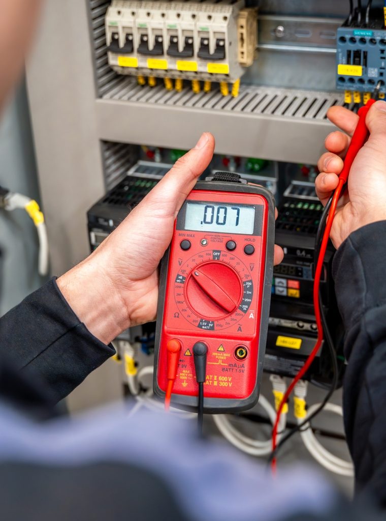 Worker measuring and repairing an electrical system panel